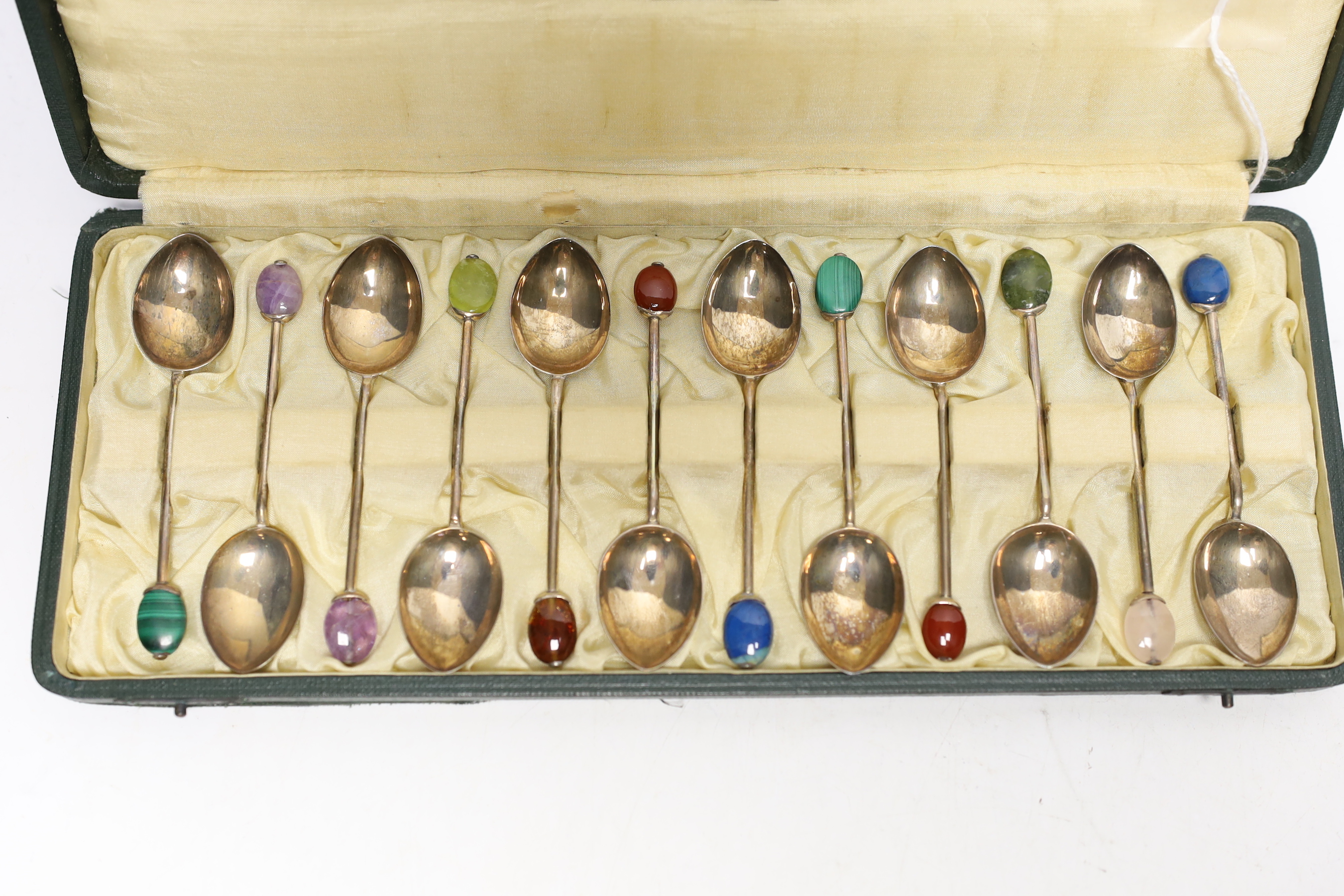 A cased set of twelve George V Liberty & Co silver coffee spoons, with gem set terminals including amethyst, malachite and carnelian, Birmingham, 1927, 93mm, in Liberty & Co box.